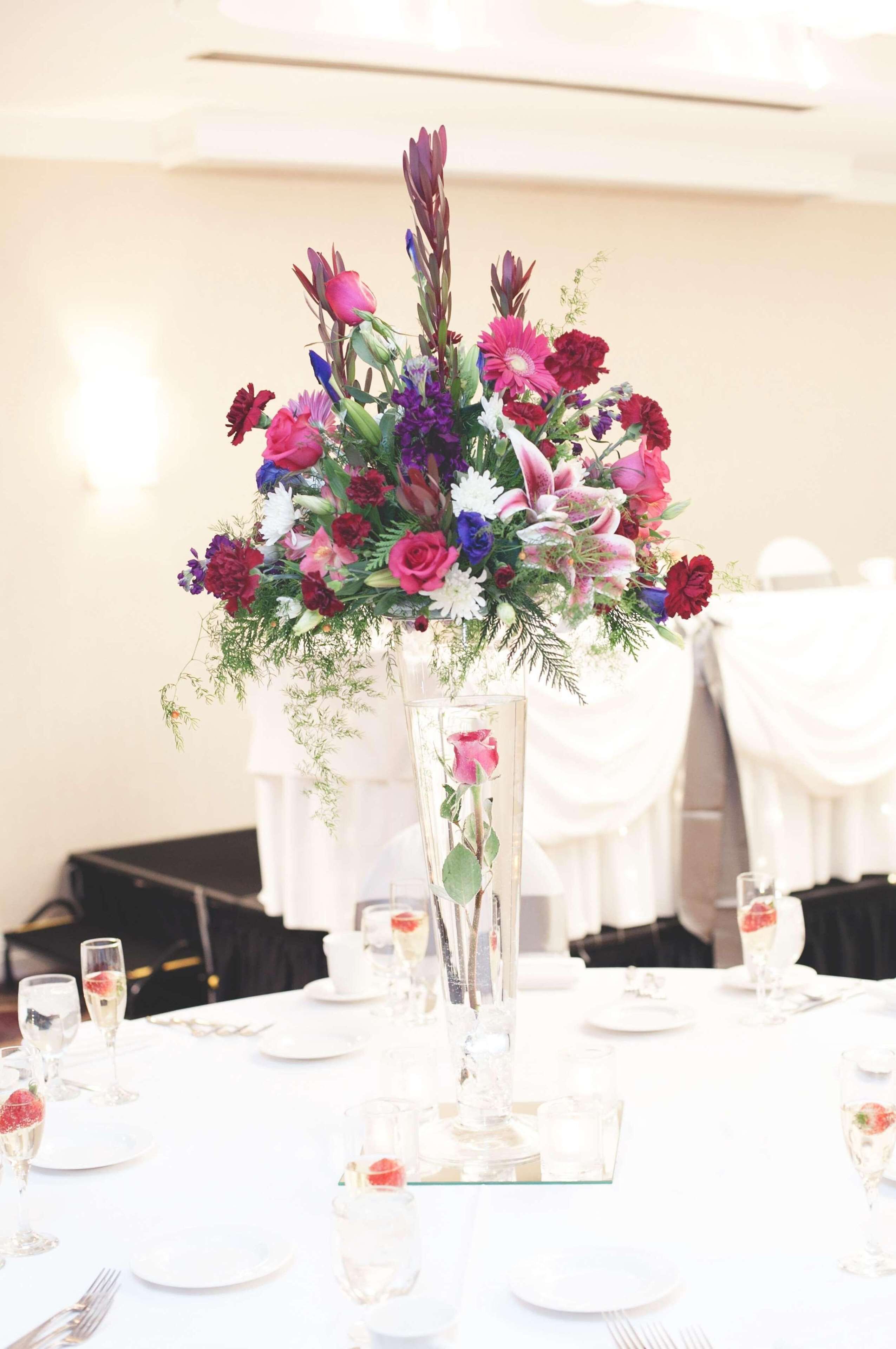 A table set for a formal event with a floral centerpiece, white tablecloths, and champagne glasses.