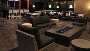 An outdoor seating area with wicker furniture, a fire feature, and ambient lighting. - Radisson Hotel Corning (Corning)