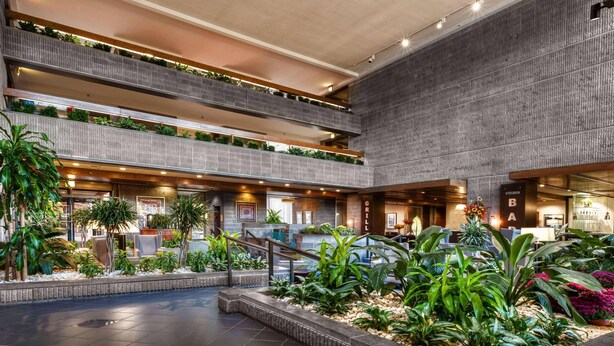 A multi-level atrium with a central garden, multiple floors, and a bar area. - Radisson Hotel Corning (Corning)