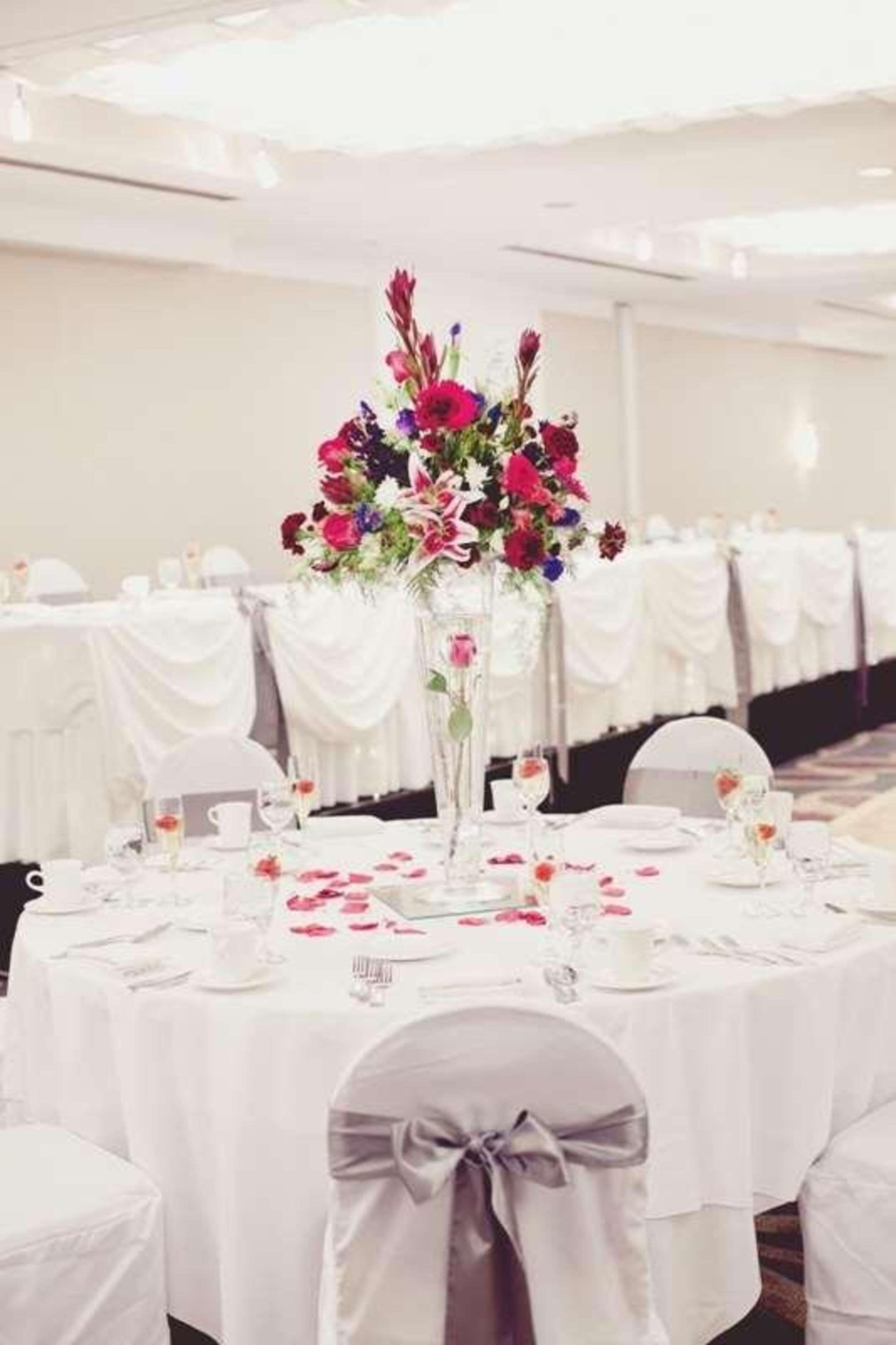 A banquet hall with round tables set for a formal event, featuring white tablecloths and floral centerpieces.