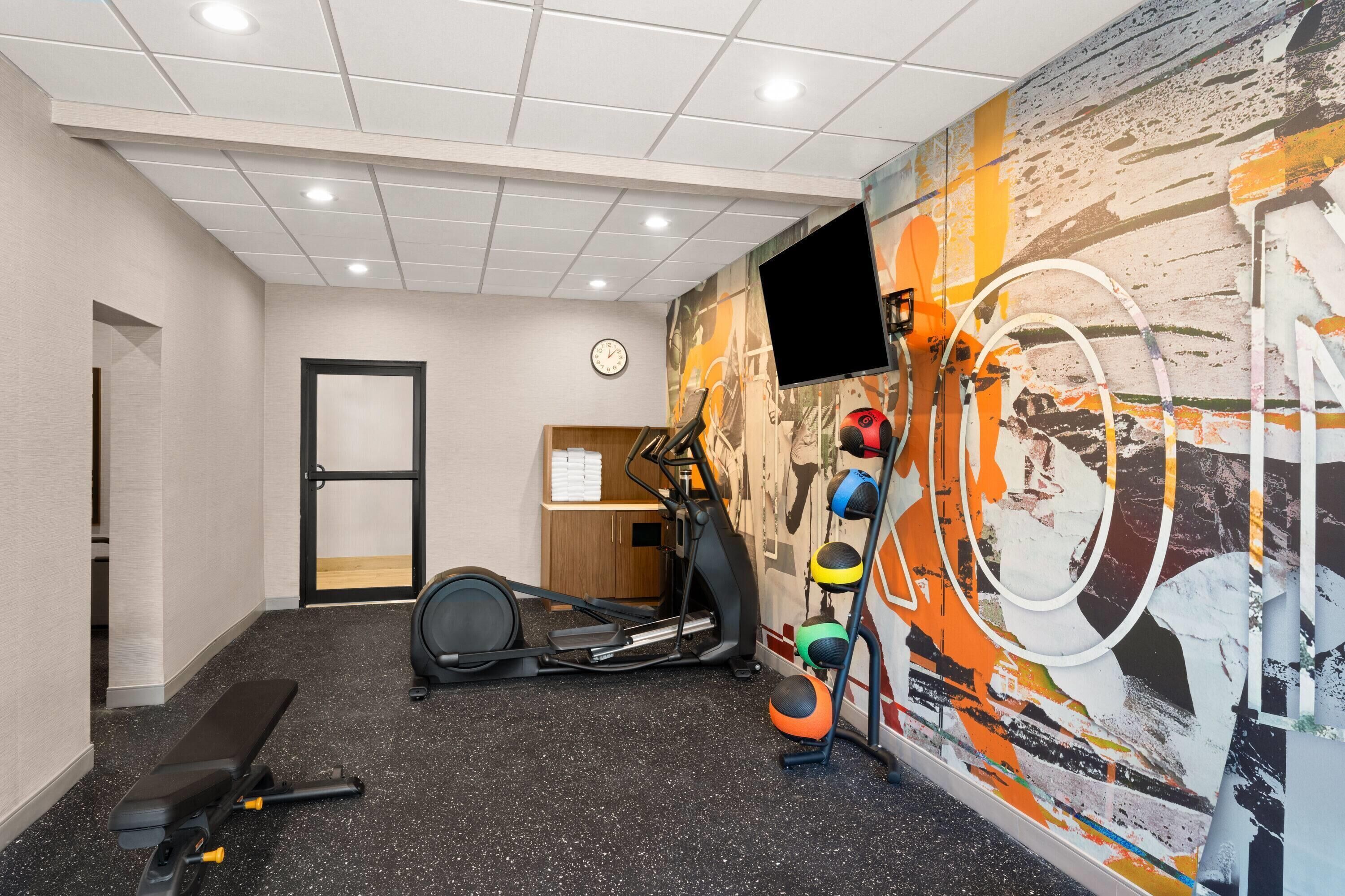 A gym with exercise equipment, a wall clock, and a television.