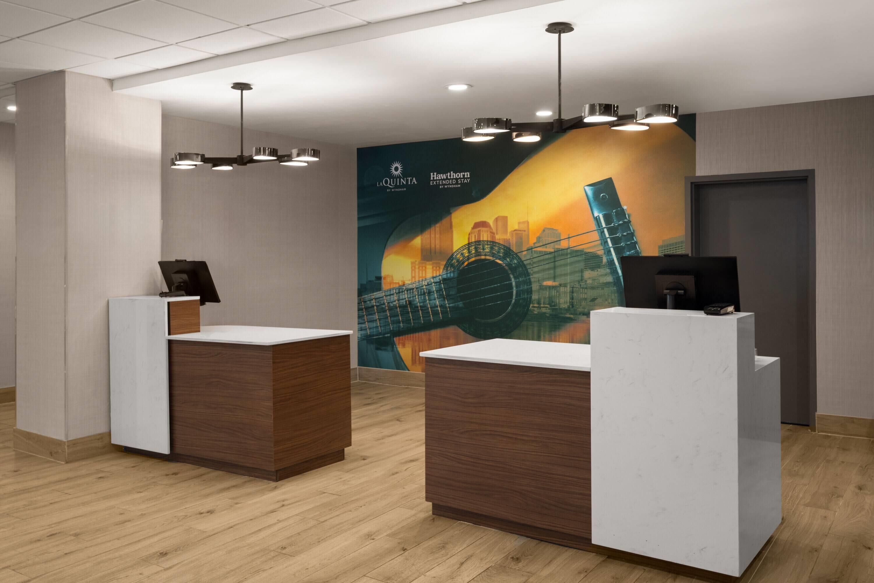 A reception area with two reception desks, a large mural, and a ceiling with recessed lighting.
