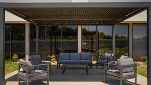 An outdoor seating area with a pergola, modern furniture, and large windows offering views of the landscape. - La Quinta Inn & Suites by Wyndham Nashville Airport/Opryland (Nashville)