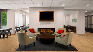 A modern lounge area with a fireplace, comfortable seating, and a large flat-screen TV. - La Quinta Inn & Suites by Wyndham Nashville Airport/Opryland (Nashville)
