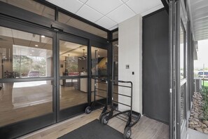 A modern hotel entrance with glass doors, a cart, and a doormat. - La Quinta Inn & Suites by Wyndham Nashville Airport/Opryland (Nashville)