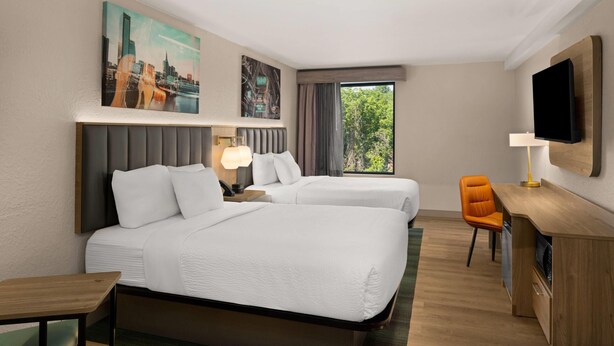 A hotel room with two beds, a desk, a chair, a TV, and a window with a view. - La Quinta Inn & Suites by Wyndham Nashville Airport/Opryland (Nashville)