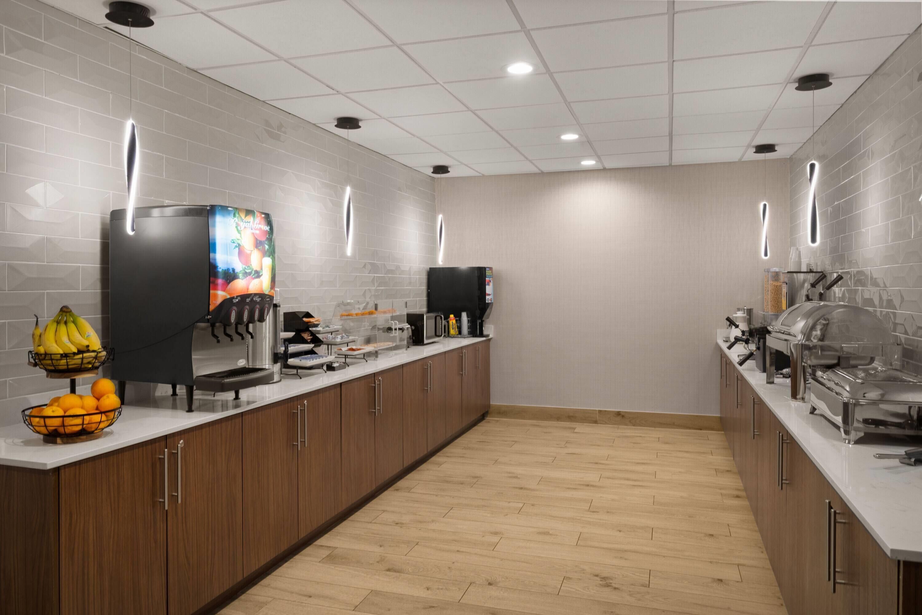 Una cocina moderna con una barra larga, una cafetera, una cesta de fruta y una zona de buffet.