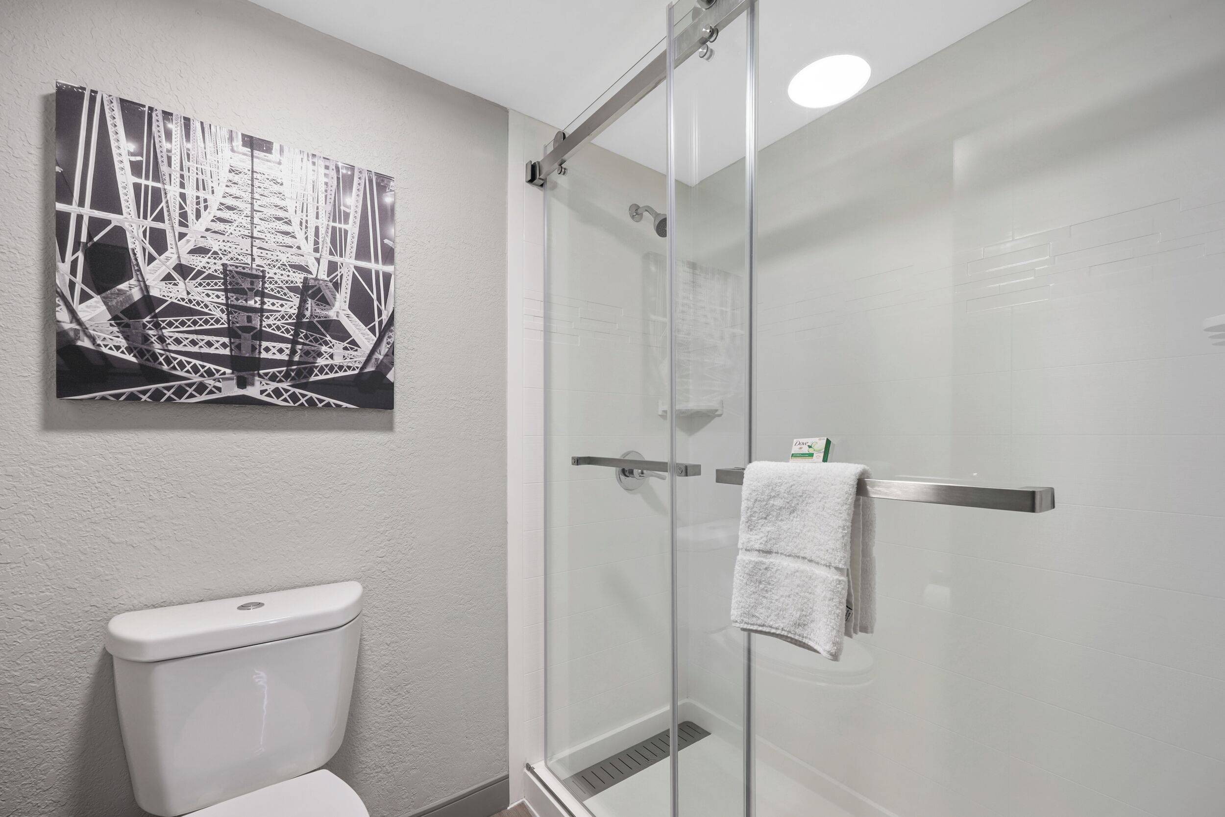 A bathroom with a glass shower enclosure, a white toilet, and a towel rack with a white towel.