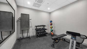 A gym with a bench, dumbbells, and a medicine ball rack.