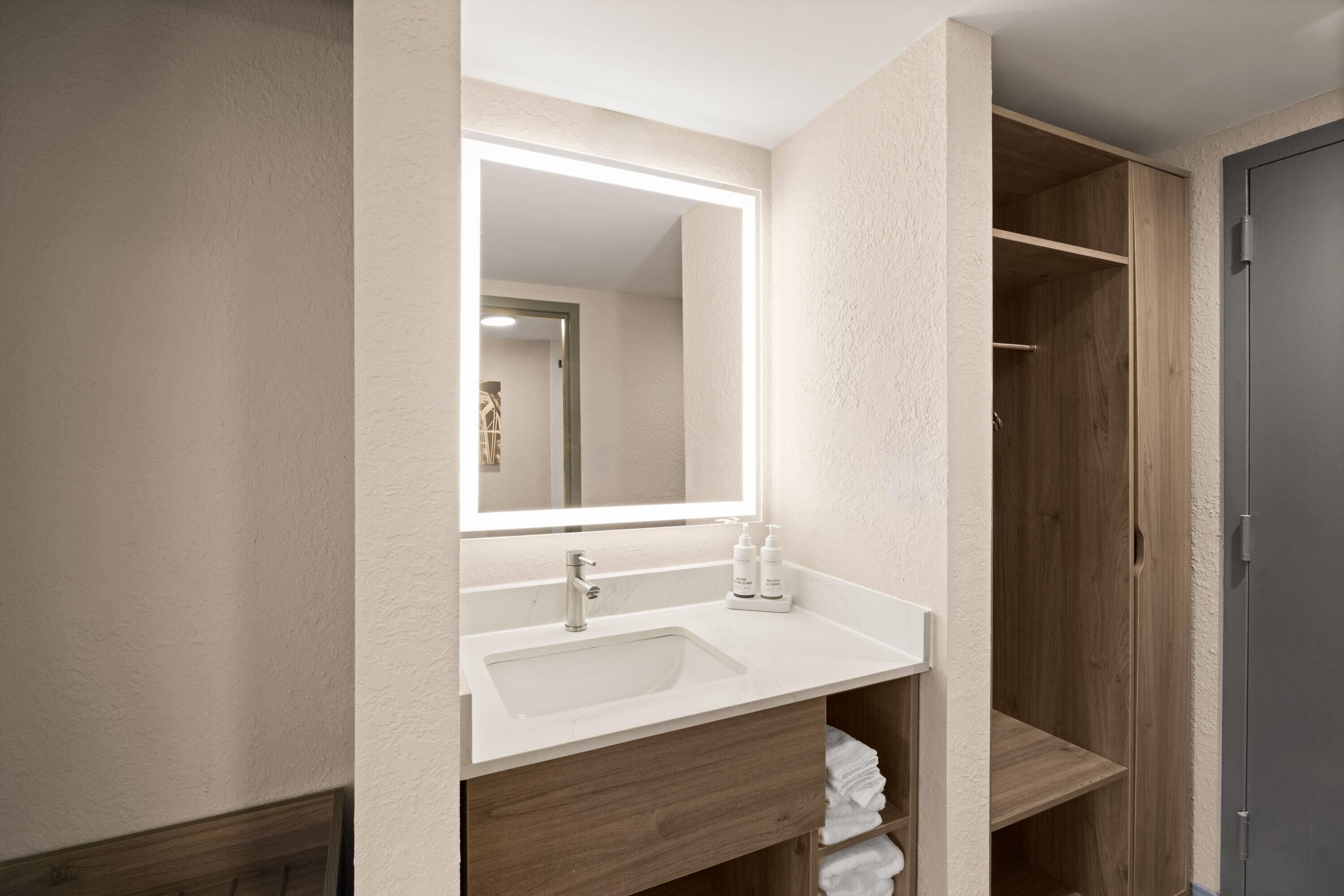 Un baño con lavabo, espejo y estanterías de madera.