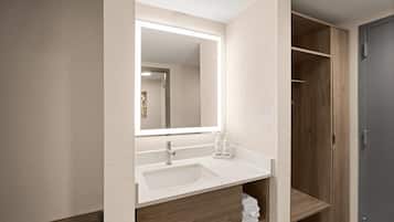 Un baño con lavabo, espejo y estanterías de madera.
