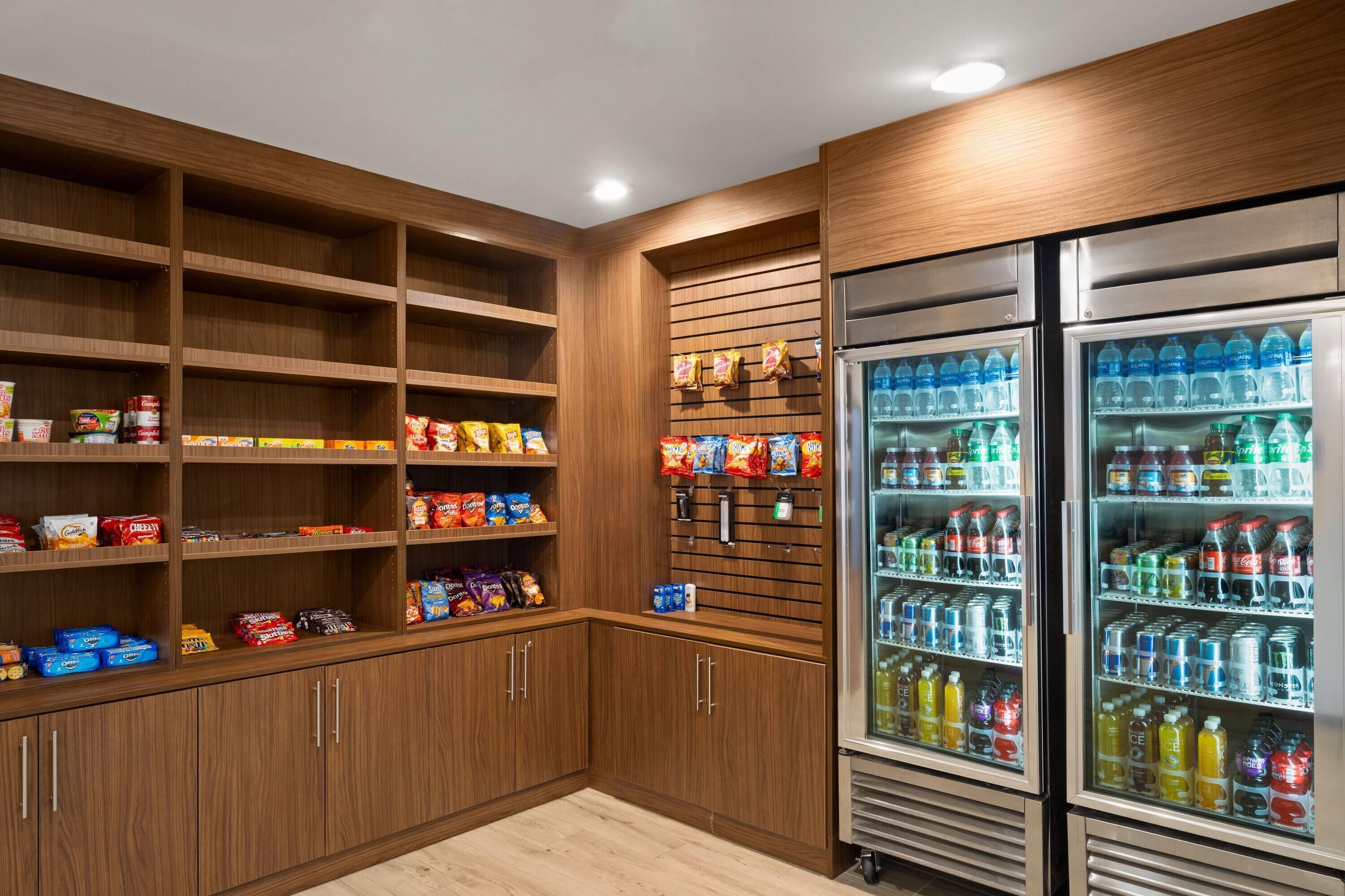 A well-organized pantry with shelves stocked with snacks and beverages, and a refrigerator filled with drinks.