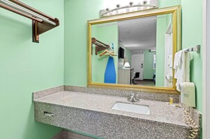 Un baño con lavabo de encimera de granito, espejo con marco dorado, toallero y secador de pelo.