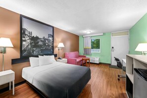 A hotel room with a bed, a desk, a chair, a lamp, and a large framed picture on the wall. - Super 8 by Wyndham Gaffney (Gaffney)