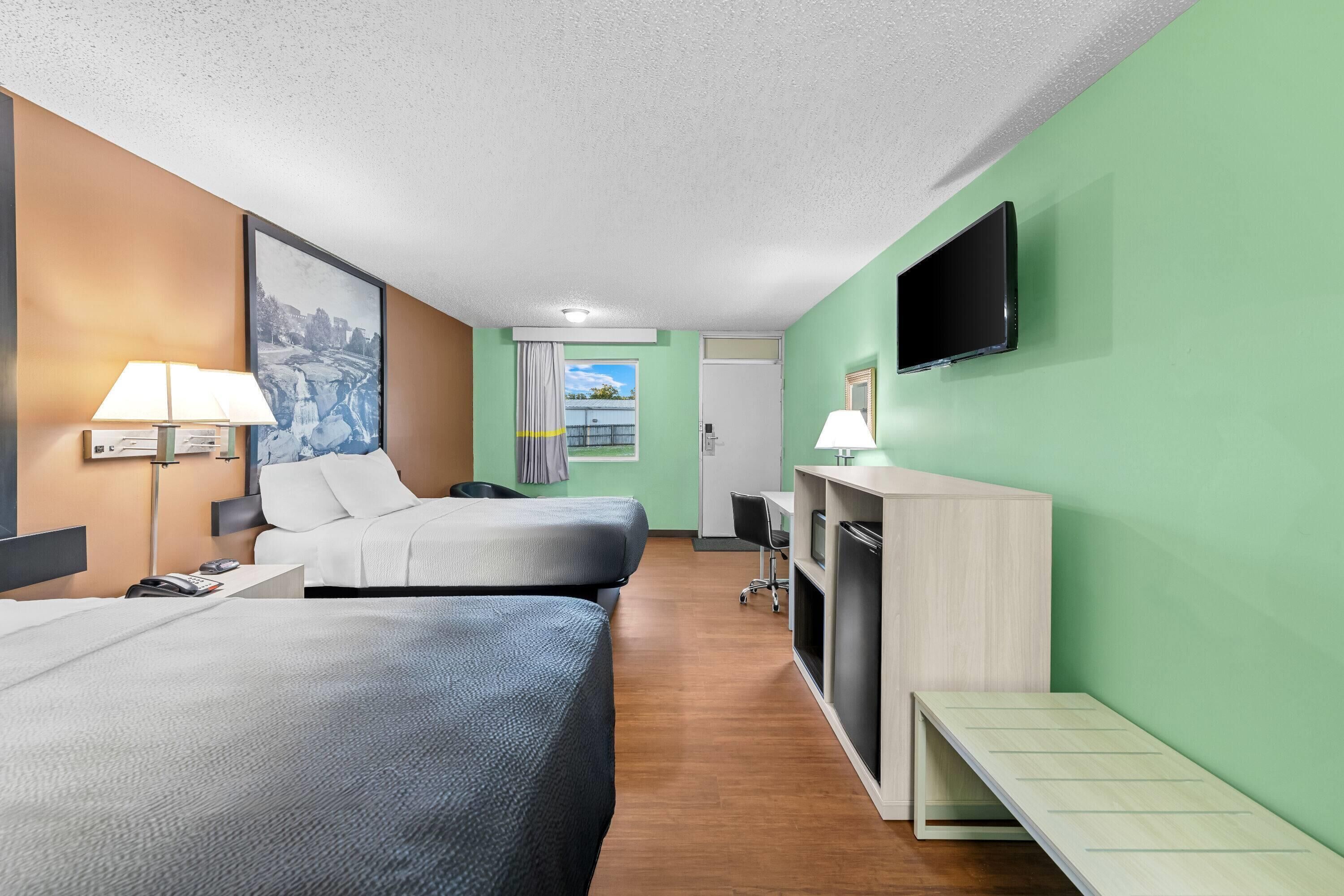 Een hotelkamer met twee bedden, een bureau, een televisie en een raam met uitzicht.