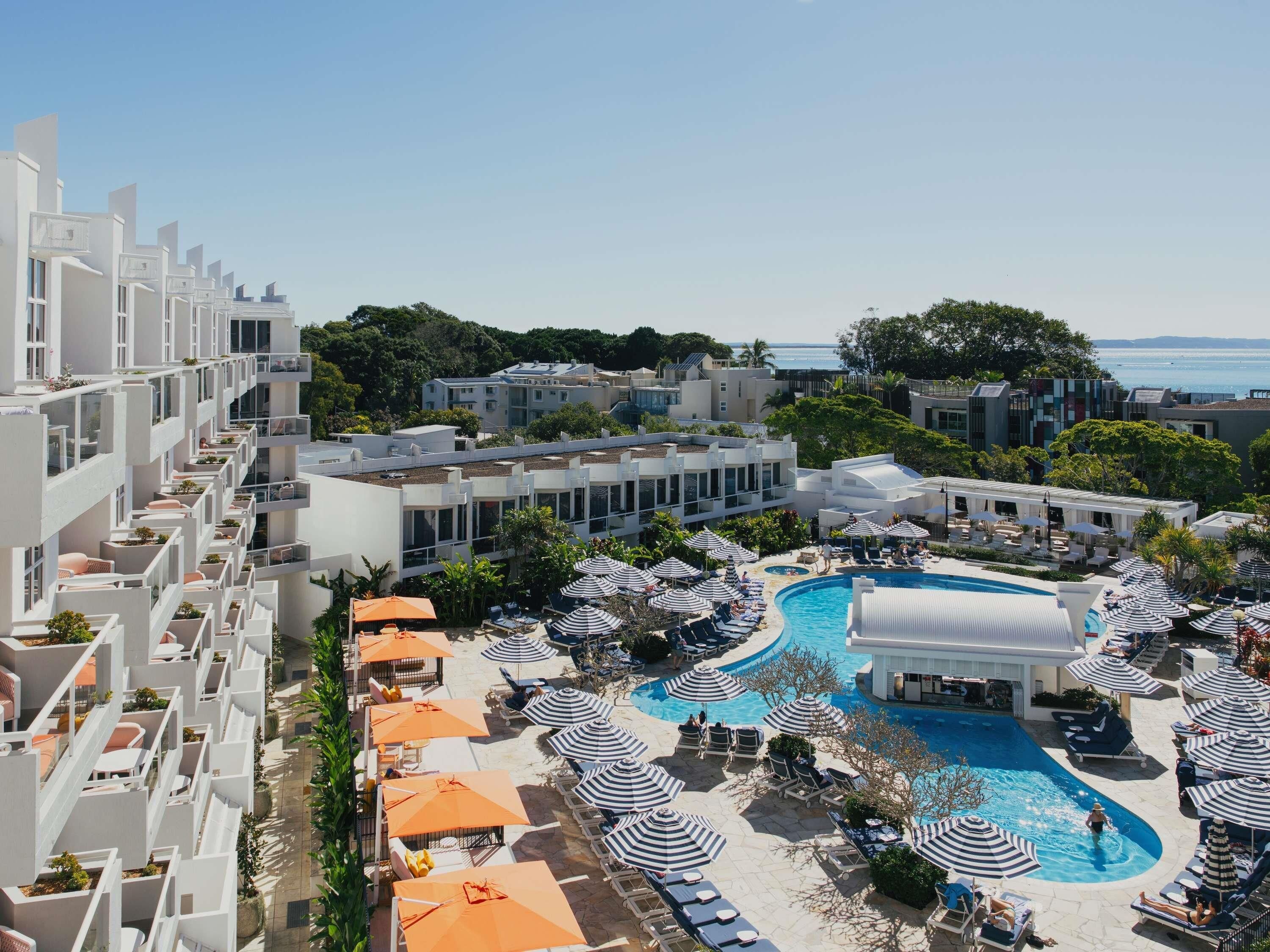A resort with a swimming pool, sun loungers, and umbrellas.