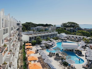A resort with a swimming pool, sun loungers, and umbrellas.