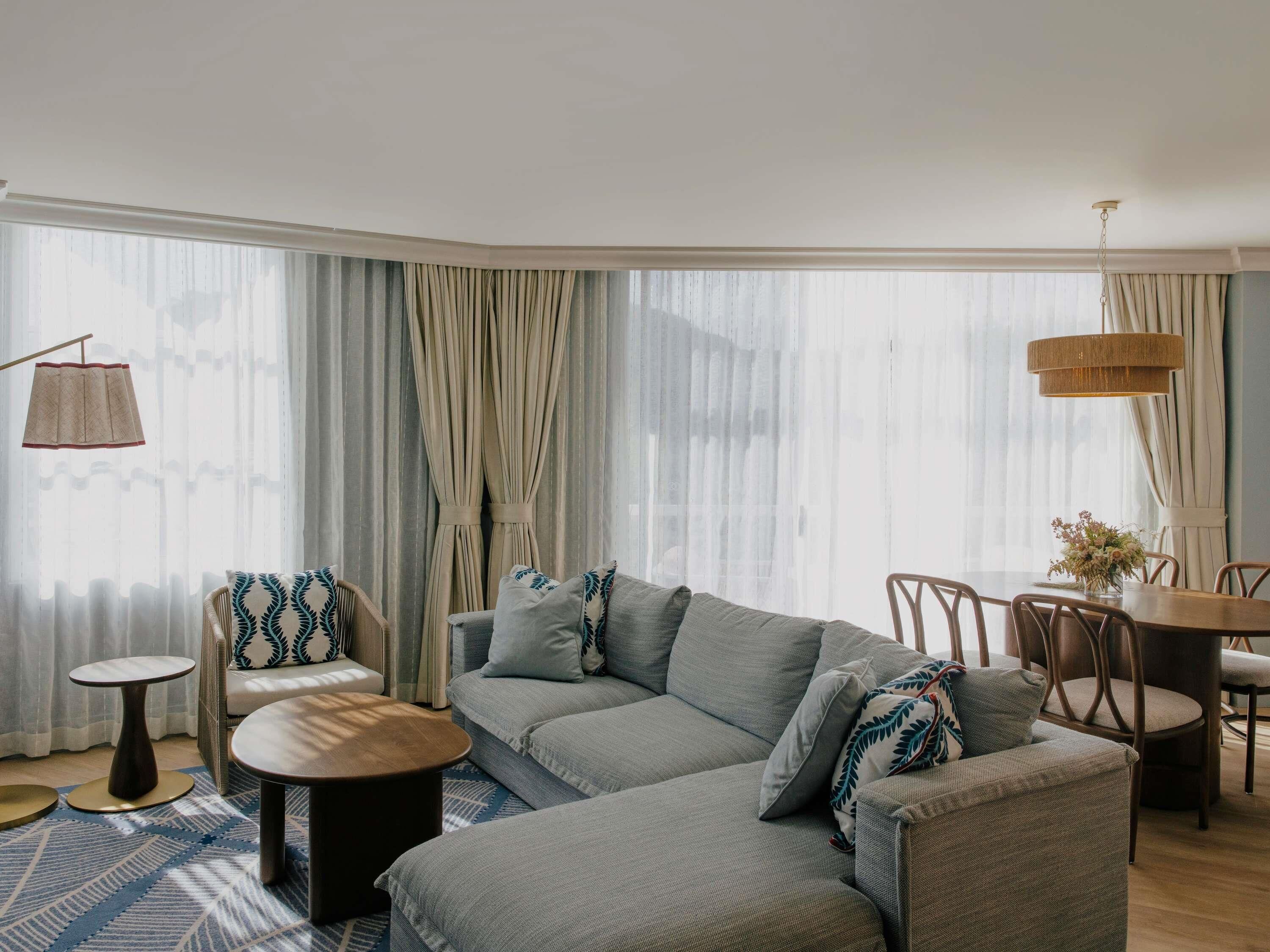 A modern living room with a sectional sofa, round coffee table, and dining area with chairs.