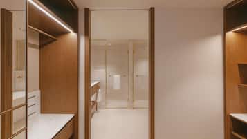 A walk-in closet with mirrored doors, wooden shelving, and a marble countertop.