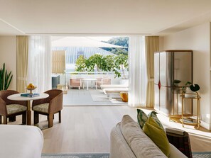 Une chambre d’hôtel avec un balcon, un canapé, une table à manger et un grand miroir.