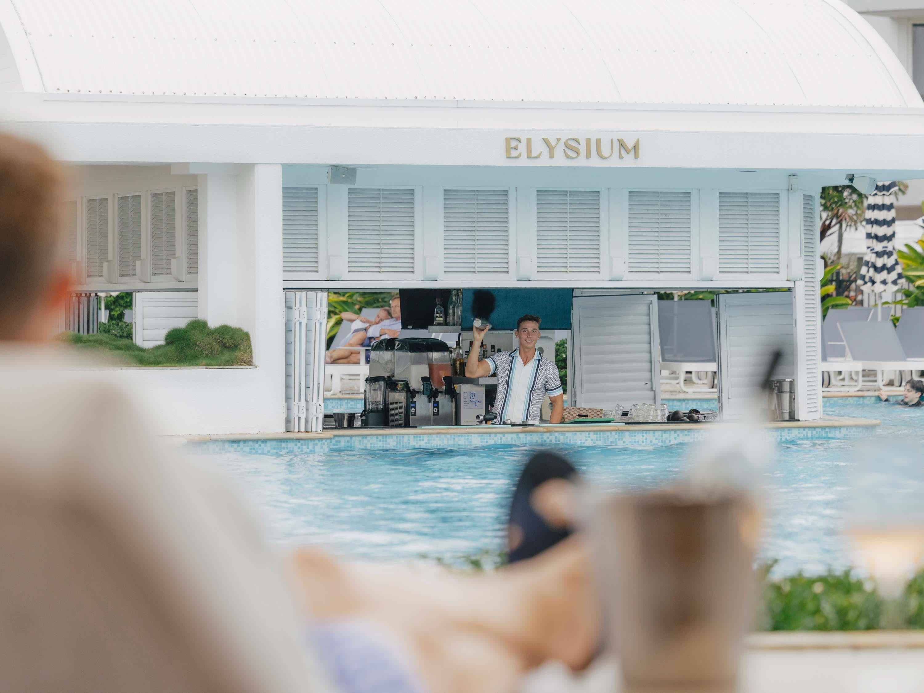Zona de piscina con bar y un letrero que dice 'ELYSIUM'.