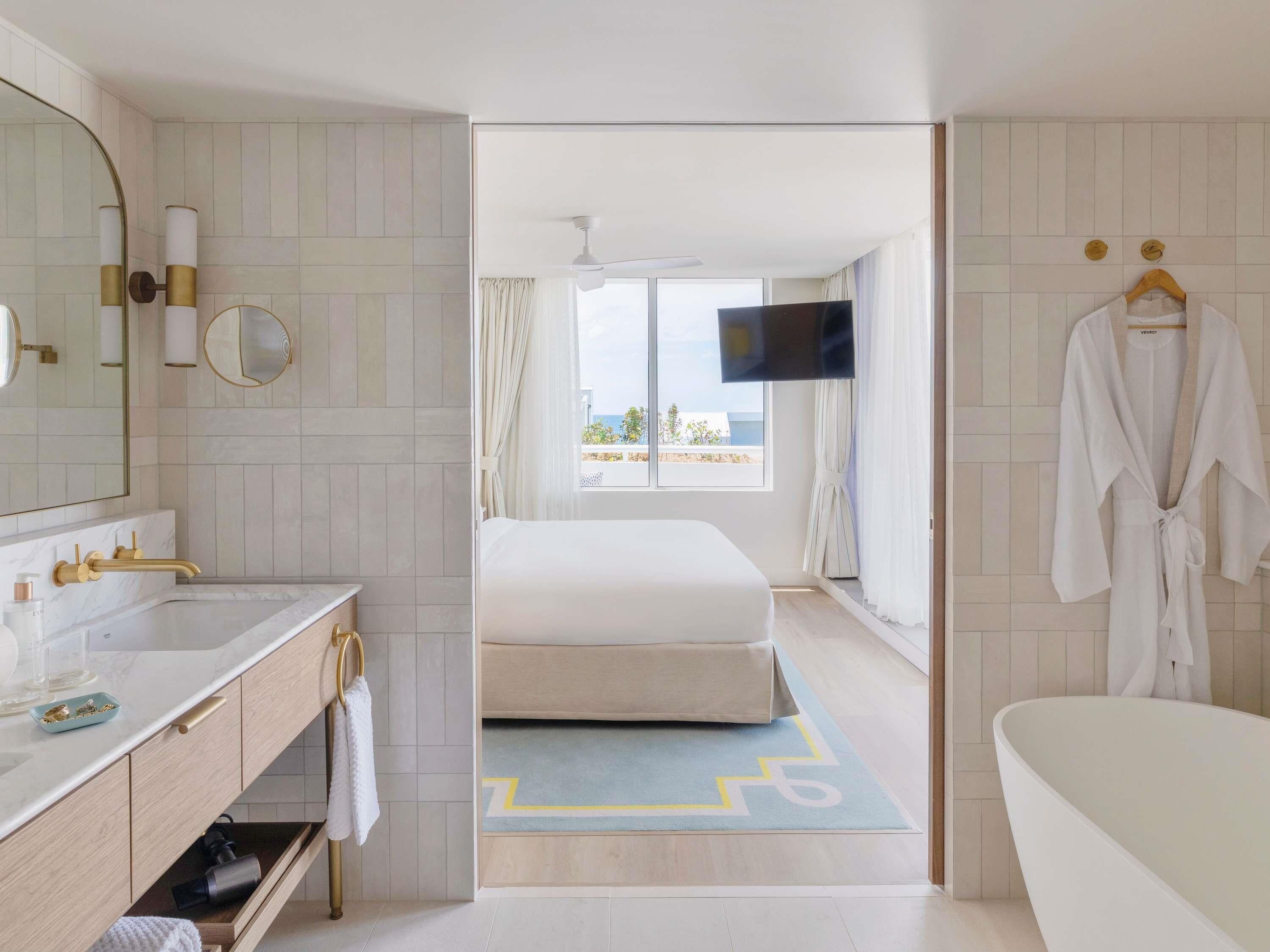 Ein Hotelzimmer mit Bad, einem Bett, einem Fernseher und Blick ins Freie.