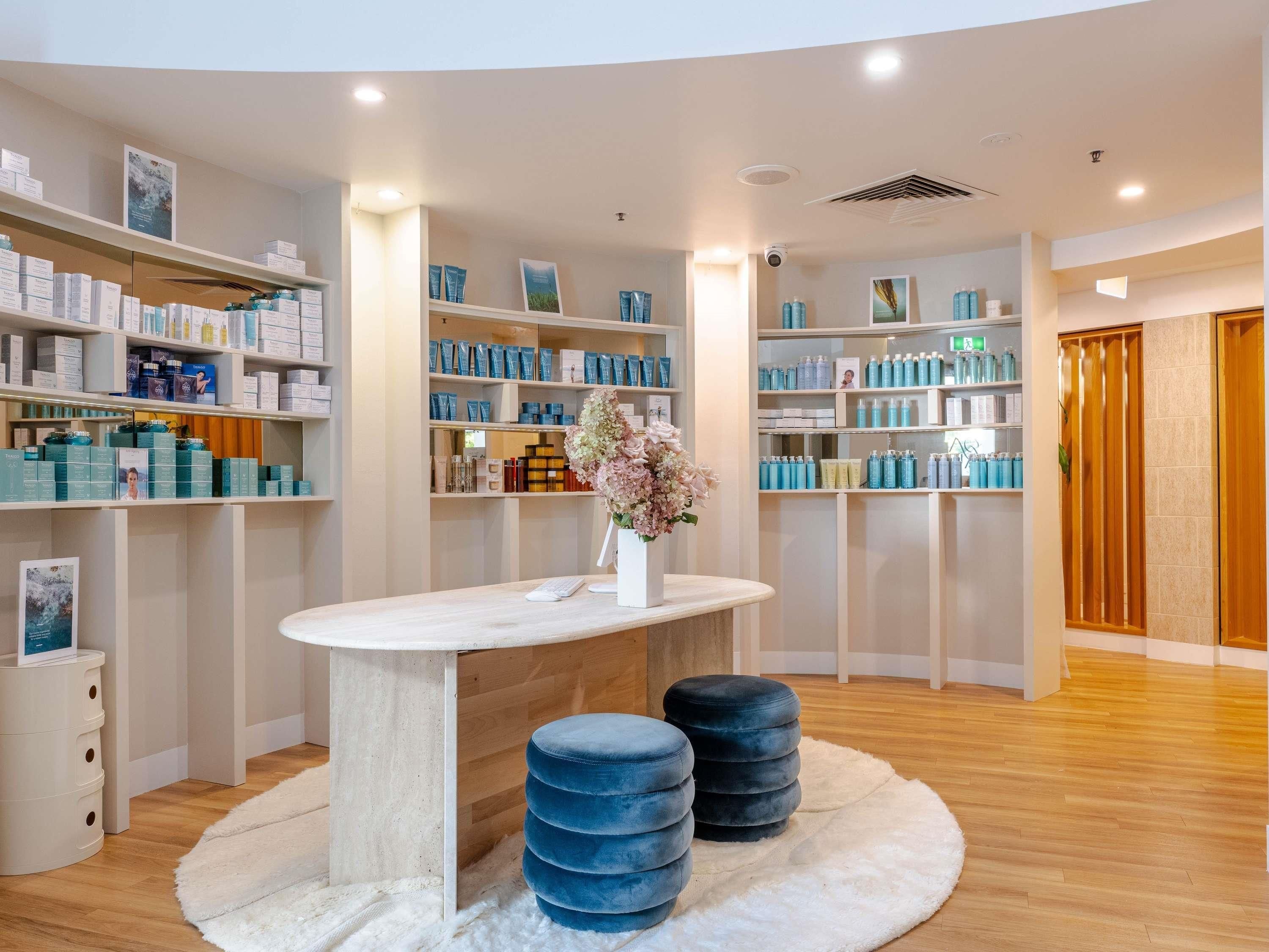 A modern retail space with shelves stocked with products, a central table with a vase, and a wooden floor.