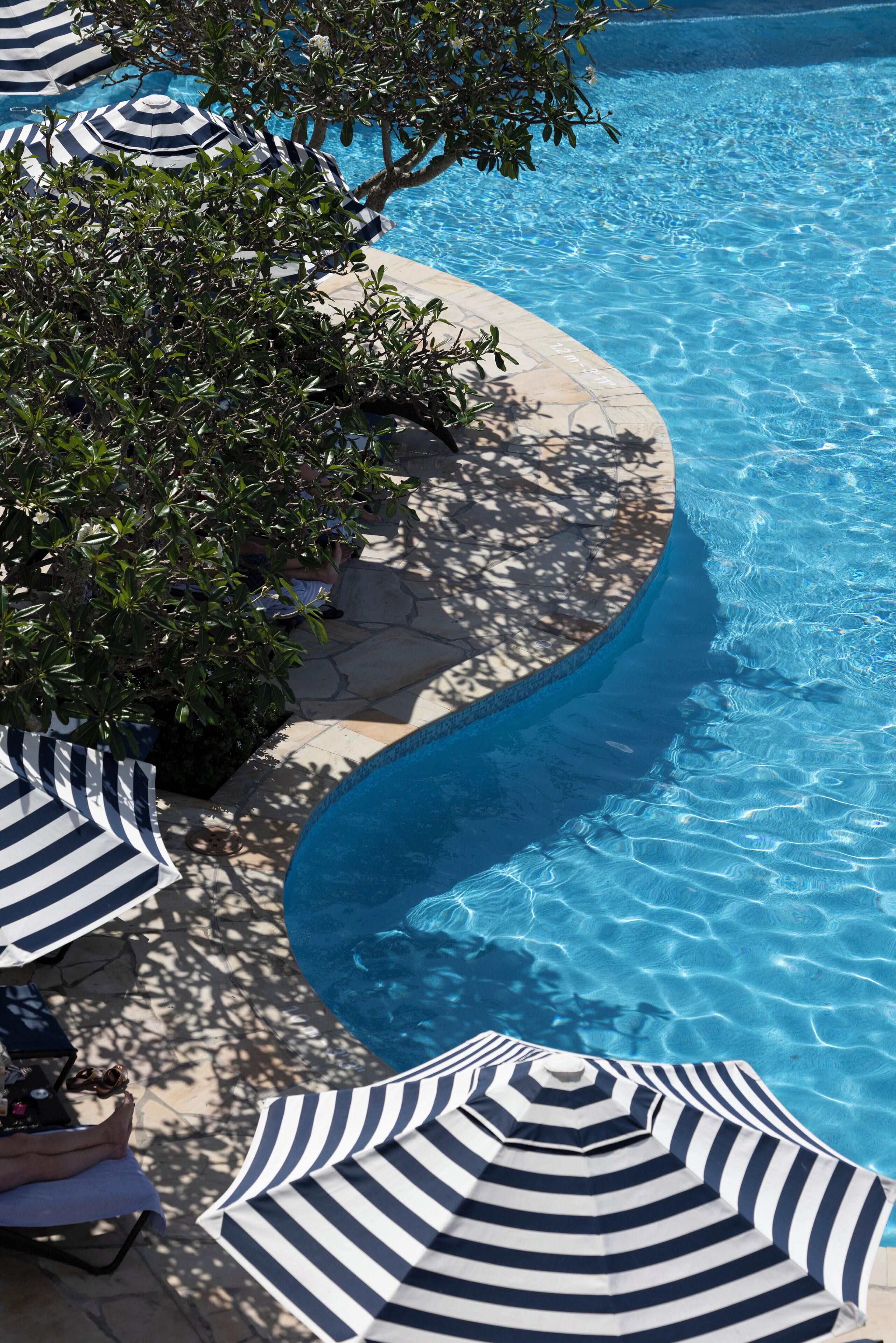 Una piscina al aire libre, camas de piscina con cargo, sombrillas