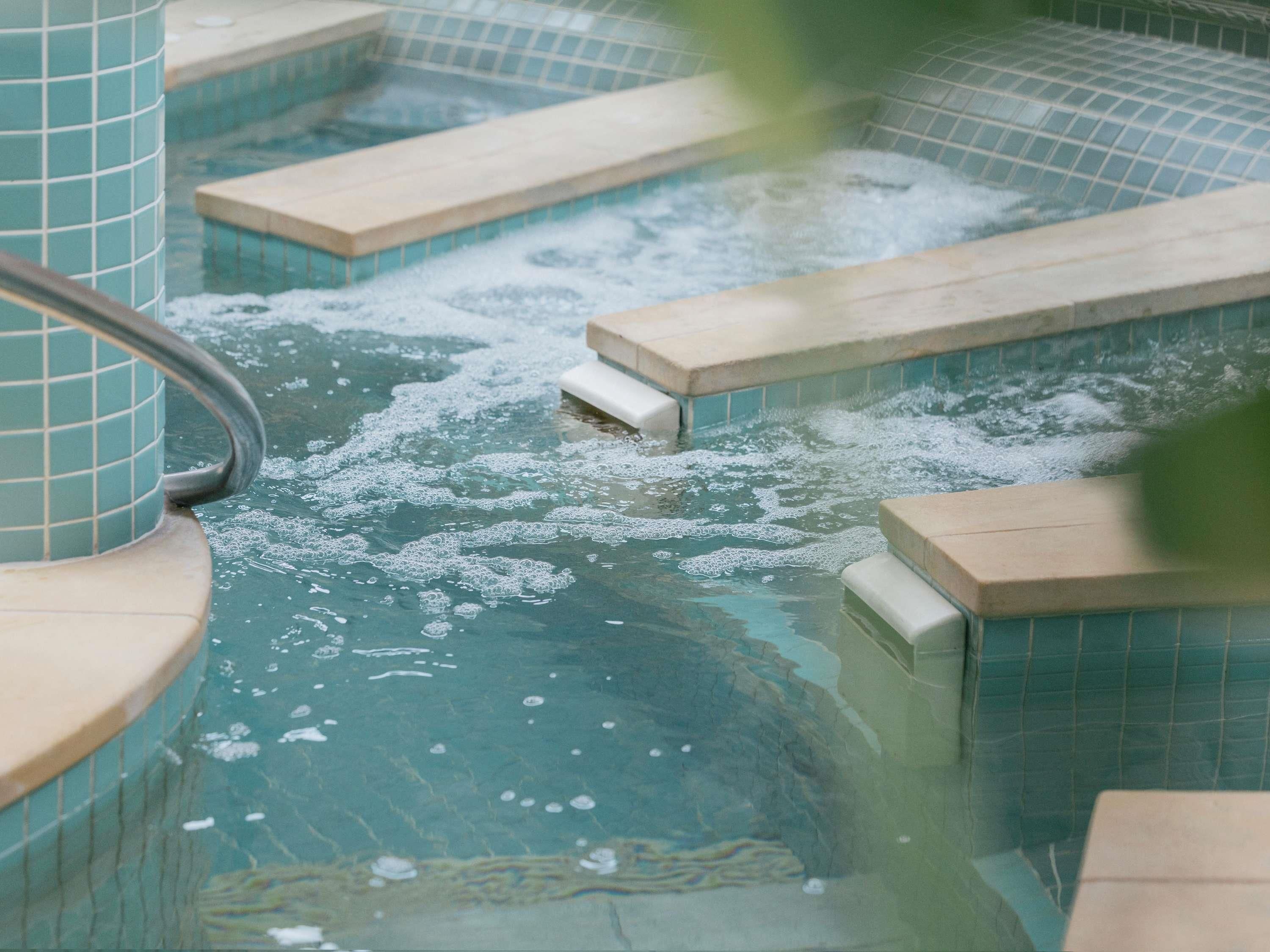 A hot tub with tiled steps and a metal railing.