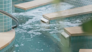A hot tub with tiled steps and a metal railing.