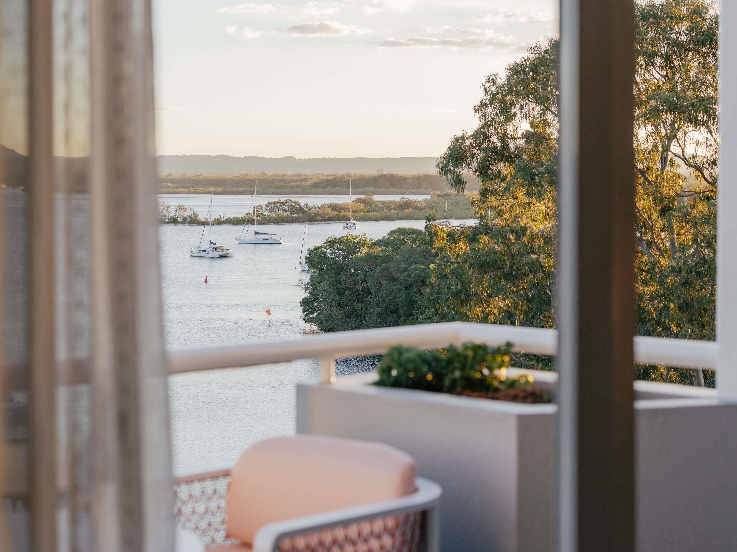 A balcony with a view of a calm body of water, boats, and trees.