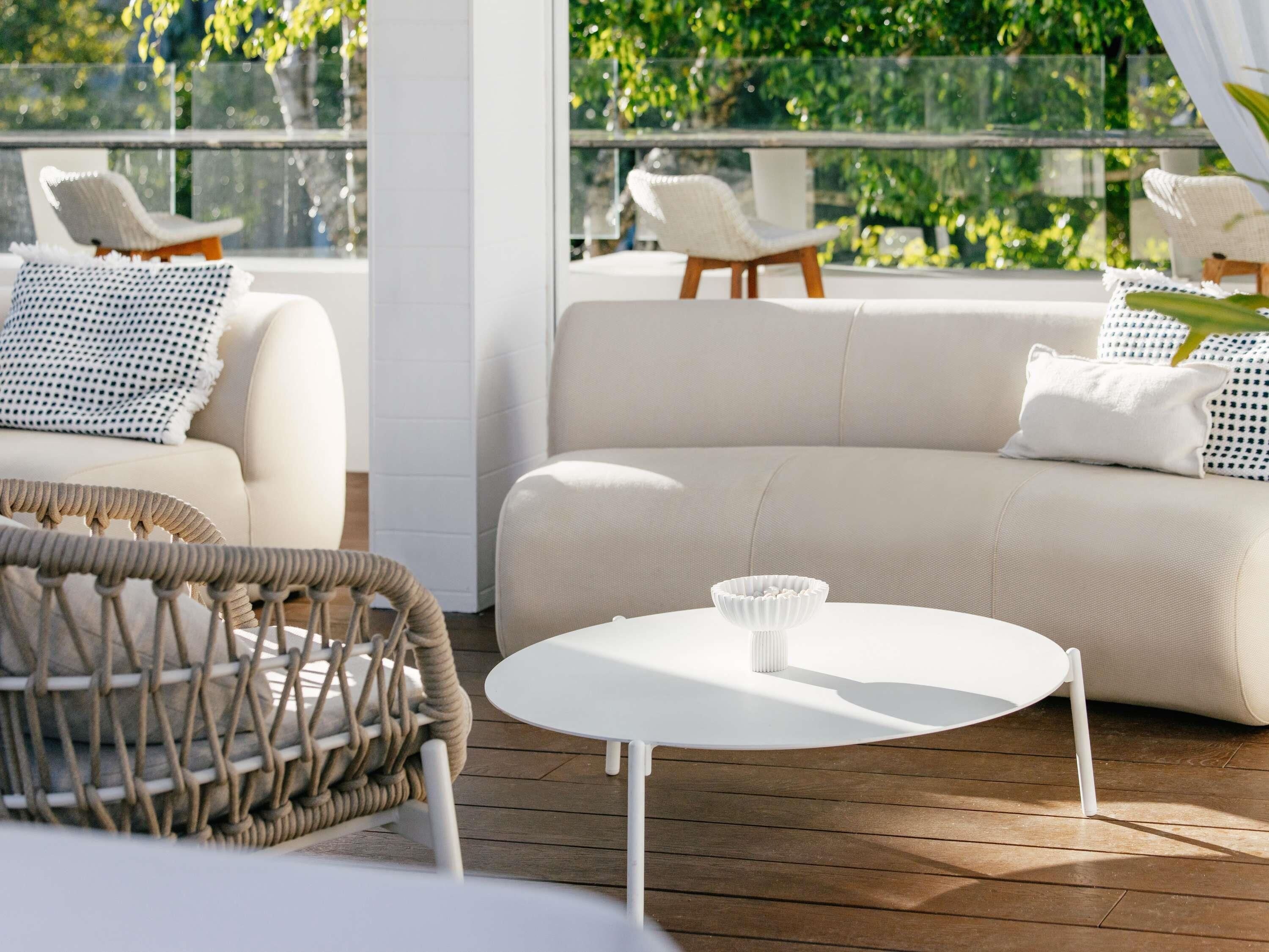 Een moderne zithoek buiten, met een bank, stoelen en een tafel.