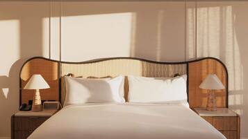 A neatly made bed with a headboard, two bedside tables with lamps, and a telephone on one of the tables.
