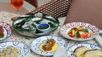 Una mesa con diversos platos, incluyendo mariscos, una copa de bebida y fuentes con diferentes comidas.
