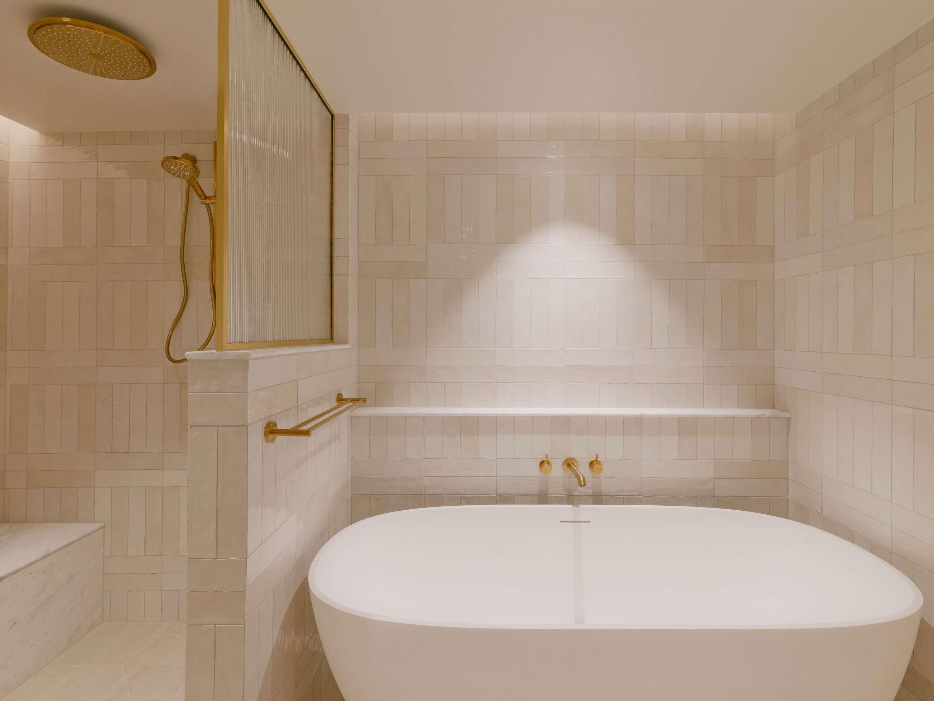 A modern bathroom with a freestanding bathtub, a showerhead, and a towel rack.