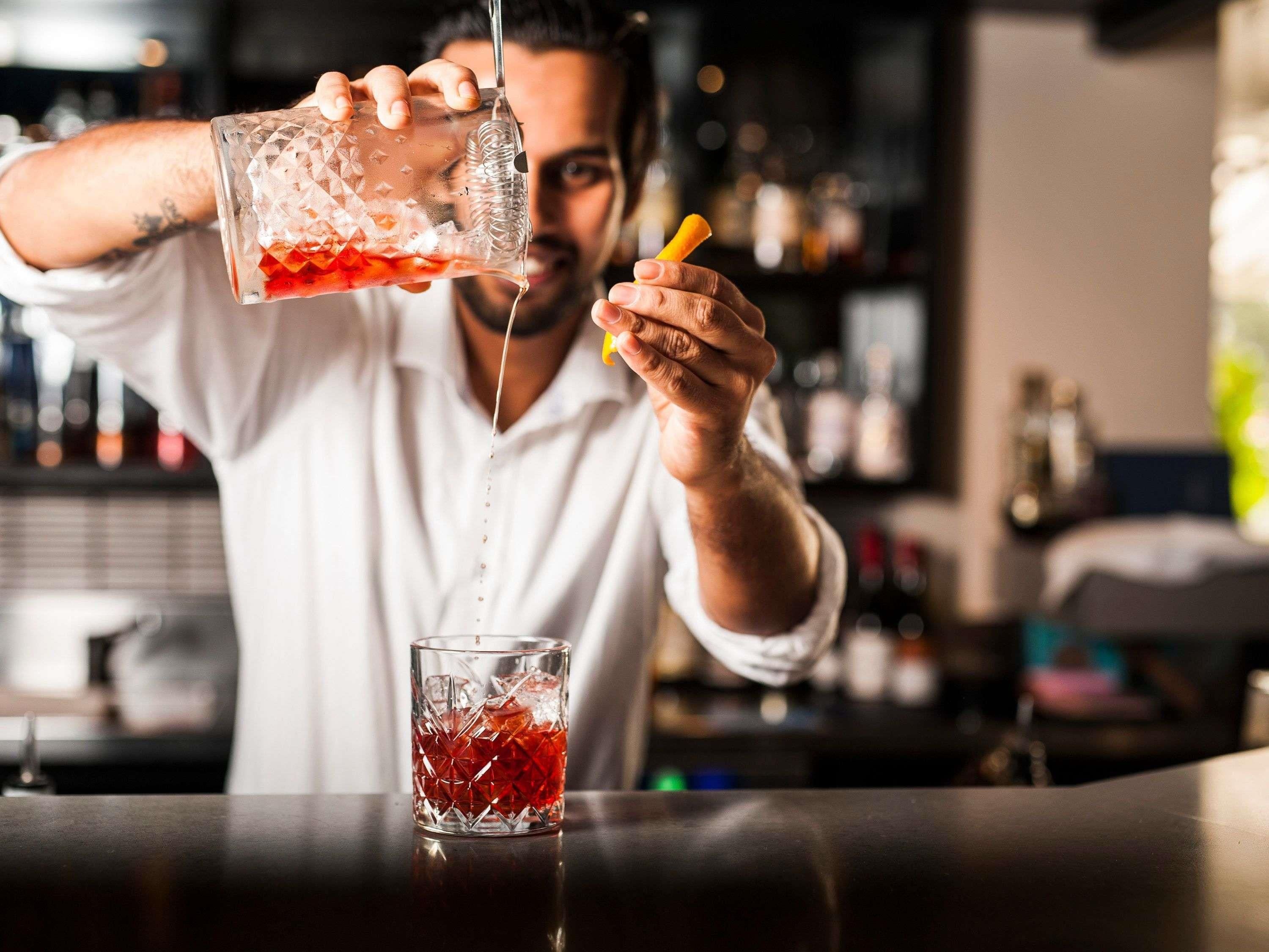 Una persona vertiendo un líquido rojo en un vaso con un diseño decorativo.