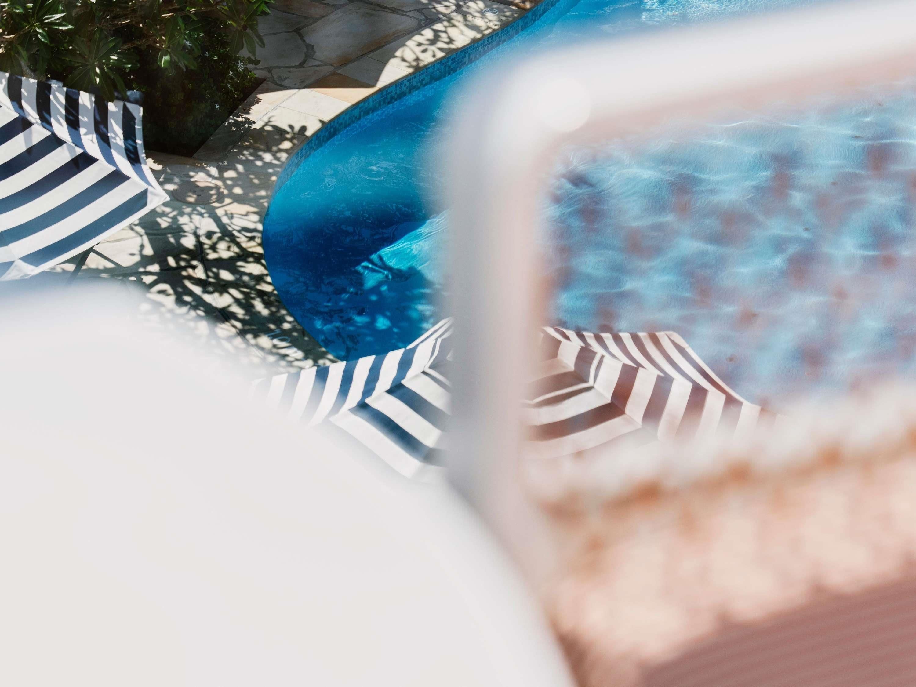 Un espace piscine avec une piscine bleue, des serviettes à rayures et une vue dégagée sur l’eau.