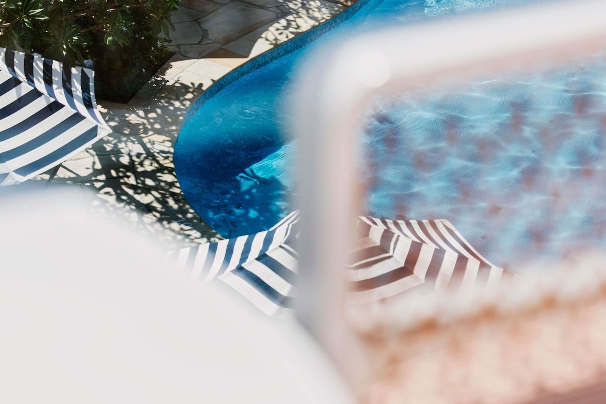 A pool area with a blue pool, striped towels, and a clear view of the water.