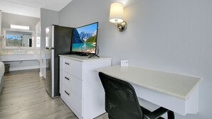 A modern kitchen with a built-in refrigerator, a flat-screen TV mounted on the wall, and a dining area with a table and chair. - Home 1 Suites Extended Stay - Kissimmee (Kissimmee)