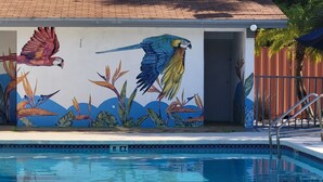 A swimming pool with a mural of parrots and tropical plants. - Home 1 Suites Extended Stay - Kissimmee (Kissimmee)