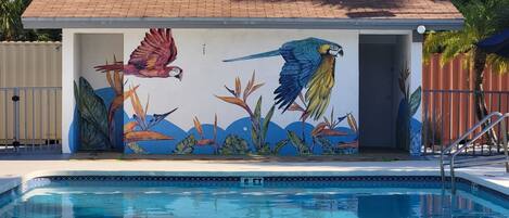 A swimming pool with a mural of parrots and tropical plants.