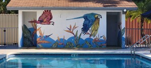 A swimming pool with a mural of parrots and tropical plants. - Home 1 Suites Extended Stay - Kissimmee (Kissimmee)