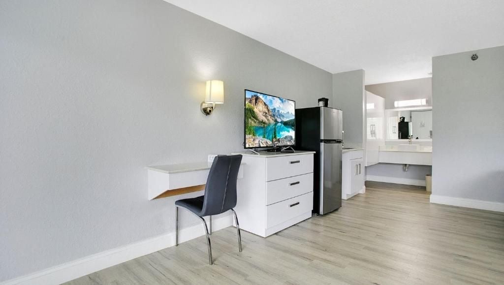 A modern kitchen with a built-in refrigerator, a flat-screen TV, and a white countertop.