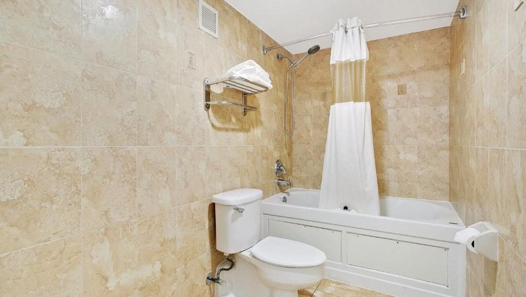 A bathroom with a toilet, bathtub, and shower curtain.