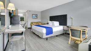 A hotel room with a bed, desk, chair, and a small round table with a chair. - Home 1 Suites Extended Stay - Kissimmee (Kissimmee)