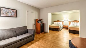 Une pièce comprenant un canapé, une petite armoire en bois, deux lits avec des lampes et une carte géographique accrochée au mur.