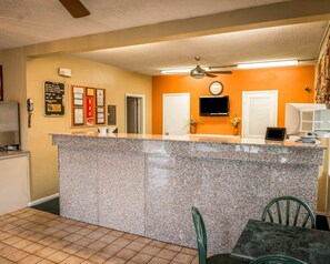 A reception area with a granite counter, a ceiling fan, a clock, and a television. - Econo Lodge Lake City-North (Lake City)