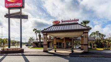 An EconoLodge with a covered entrance, palm trees, and a clear sky.