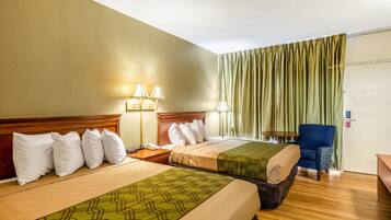 Quarto de hotel com duas camas, uma escrivaninha, uma cadeira e uma janela com cortinas.