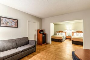 A hotel room with a sofa, a microwave, a refrigerator, and two beds with lamps. - Econo Lodge Lake City-North (Lake City)